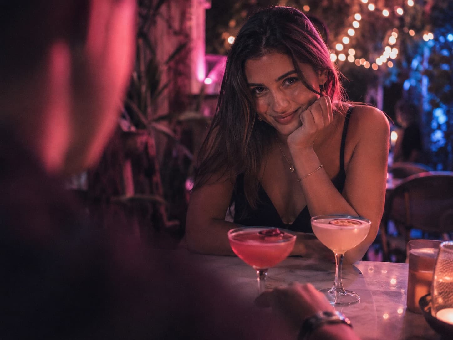 A beautiful restaurant date scene with an AI woman smiling across the table, cinematic romantic lighting.
